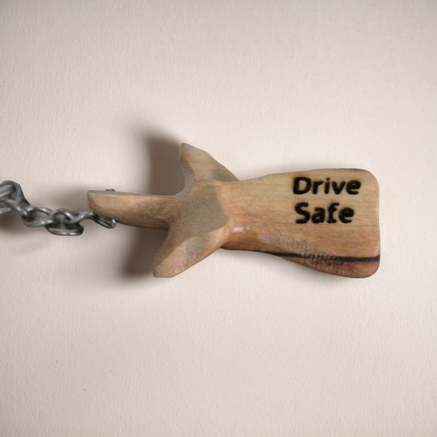 a wooden keychain with a shark on it that says drive safe