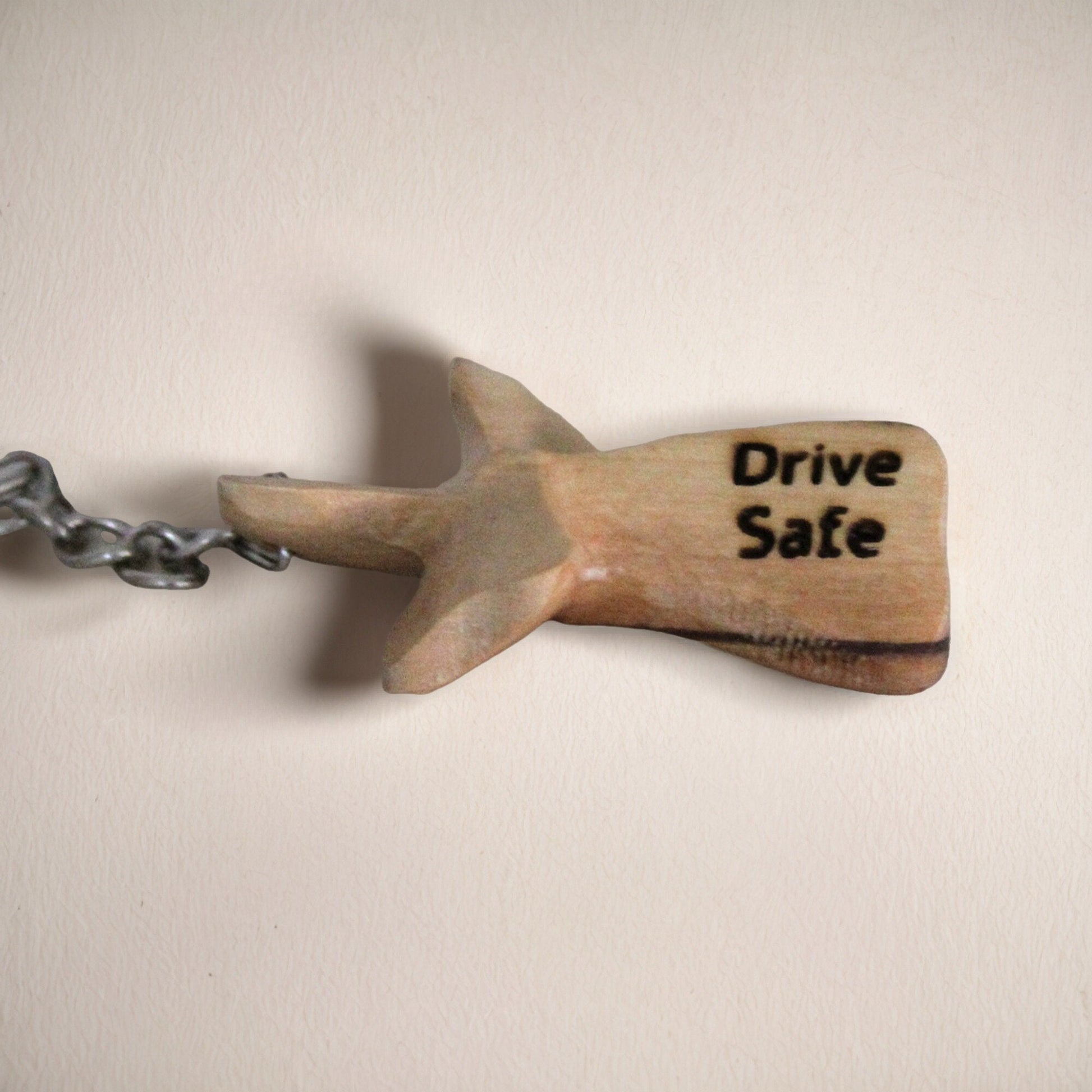 a wooden keychain with a shark on it that says drive safe